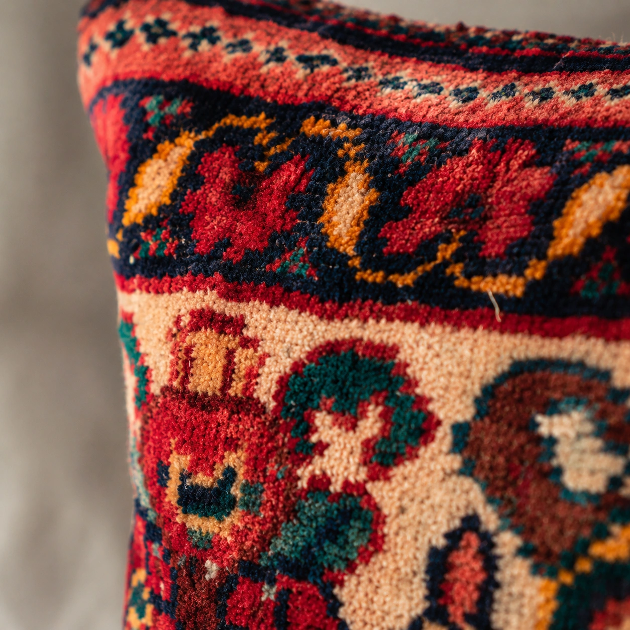 Macro close-up of Persian handwoven rug cushion showing detailed knots, wool texture, and rich colors